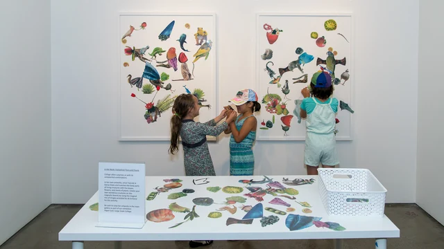 Children assembling a large collage from colourful cut-out photographs at an art centre.