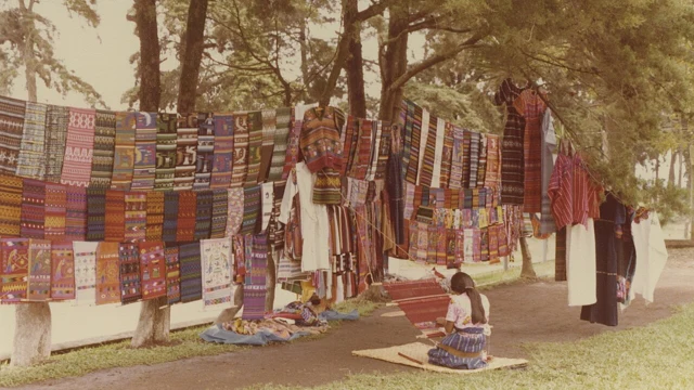 Colourful woven textiles displayed beside a traditional loom.