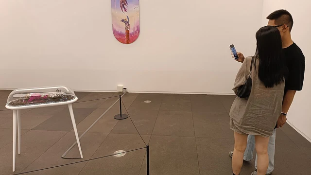 Visitors looking at artworks inside a contemporary art gallery.