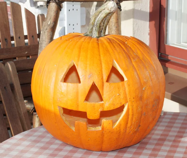 Orange Halloween pumpkin carved into a smiling jack-o’-lantern.