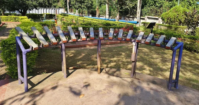Curved row of outdoor metal musical keys with attached mallets.