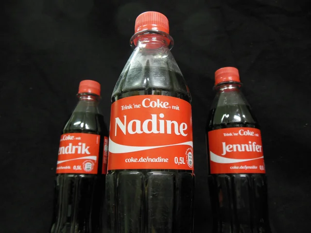 Three personalised Coca-Cola bottles with red labels.
