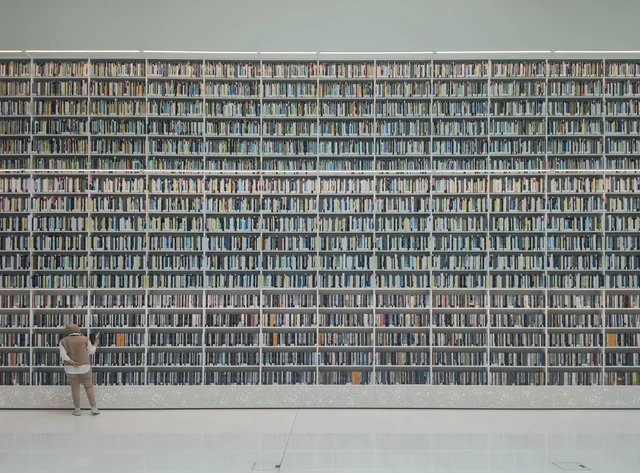 A visitor beside the tall book wall inside Mohammed Bin Rashid Library.
