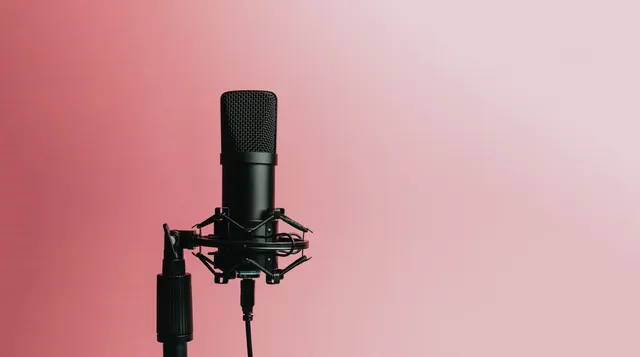 A microphone against a bright pink background, ready for a hosted quiz.