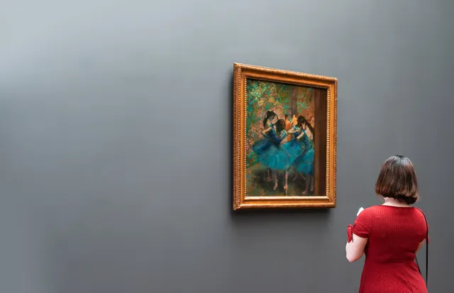 A visitor studying a framed painting in a gallery.