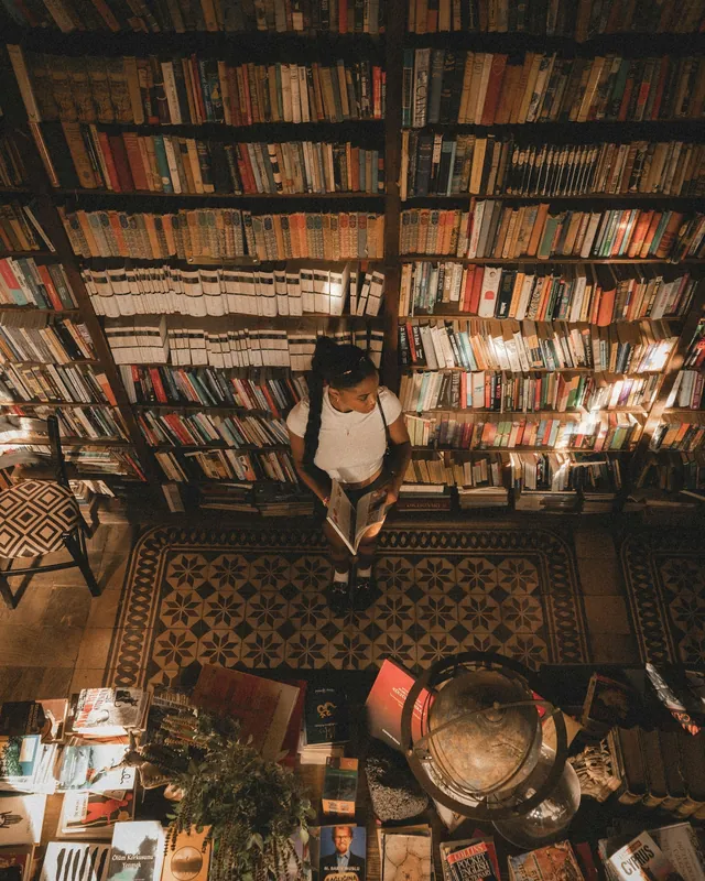 Representative reading activity: a seated reader surrounded by bookshelves; not the listed venue.