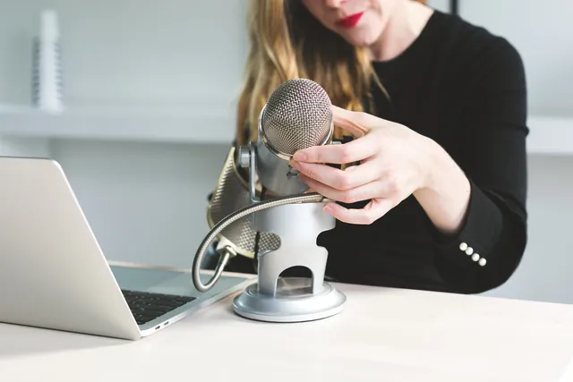 A woman preparing a microphone for a hosted event.